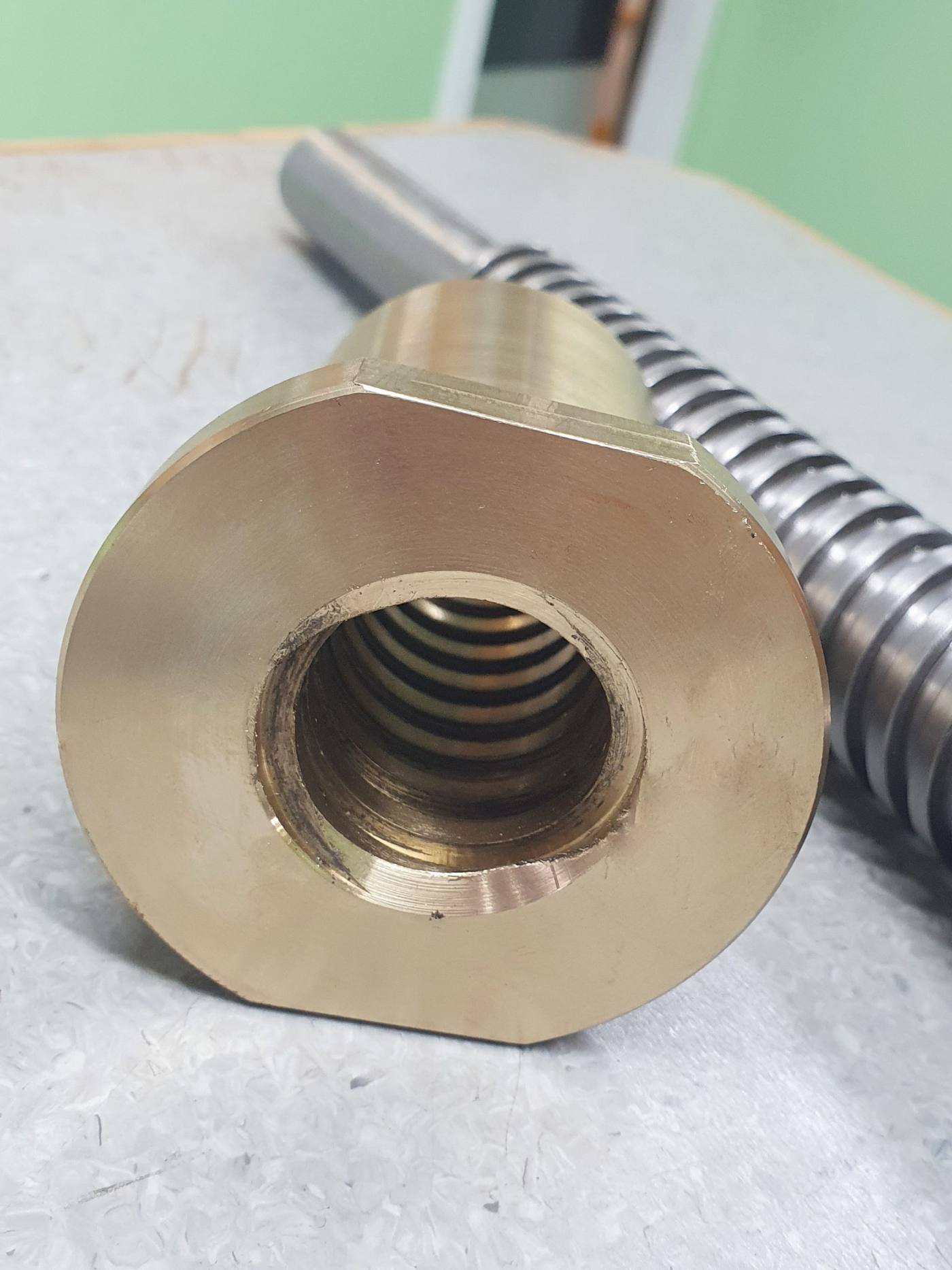 Machined bronze nut beside a threaded shaft