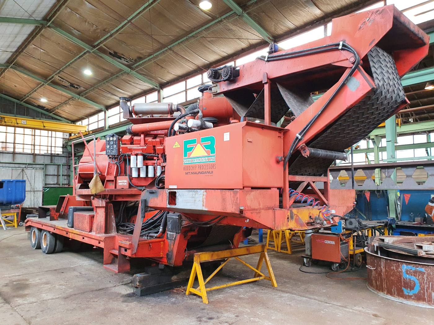 Large red processing machine being worked on in the workshop