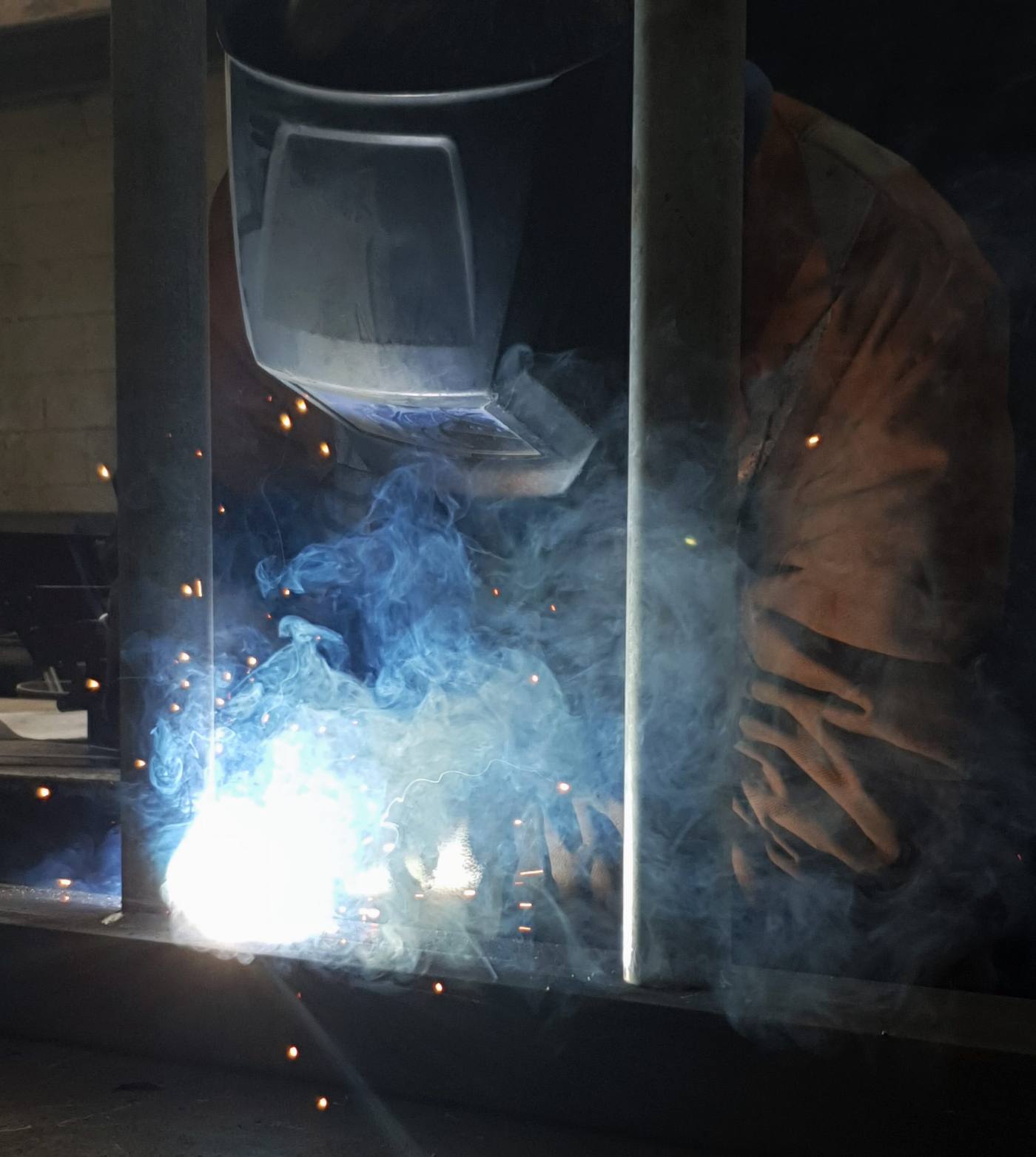Welder repairing steel with sparks flying